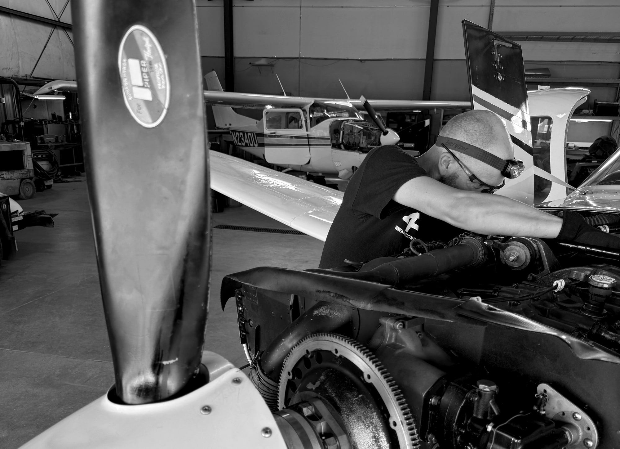 Mechanic deep in the engine of a piston single with the propeller removed