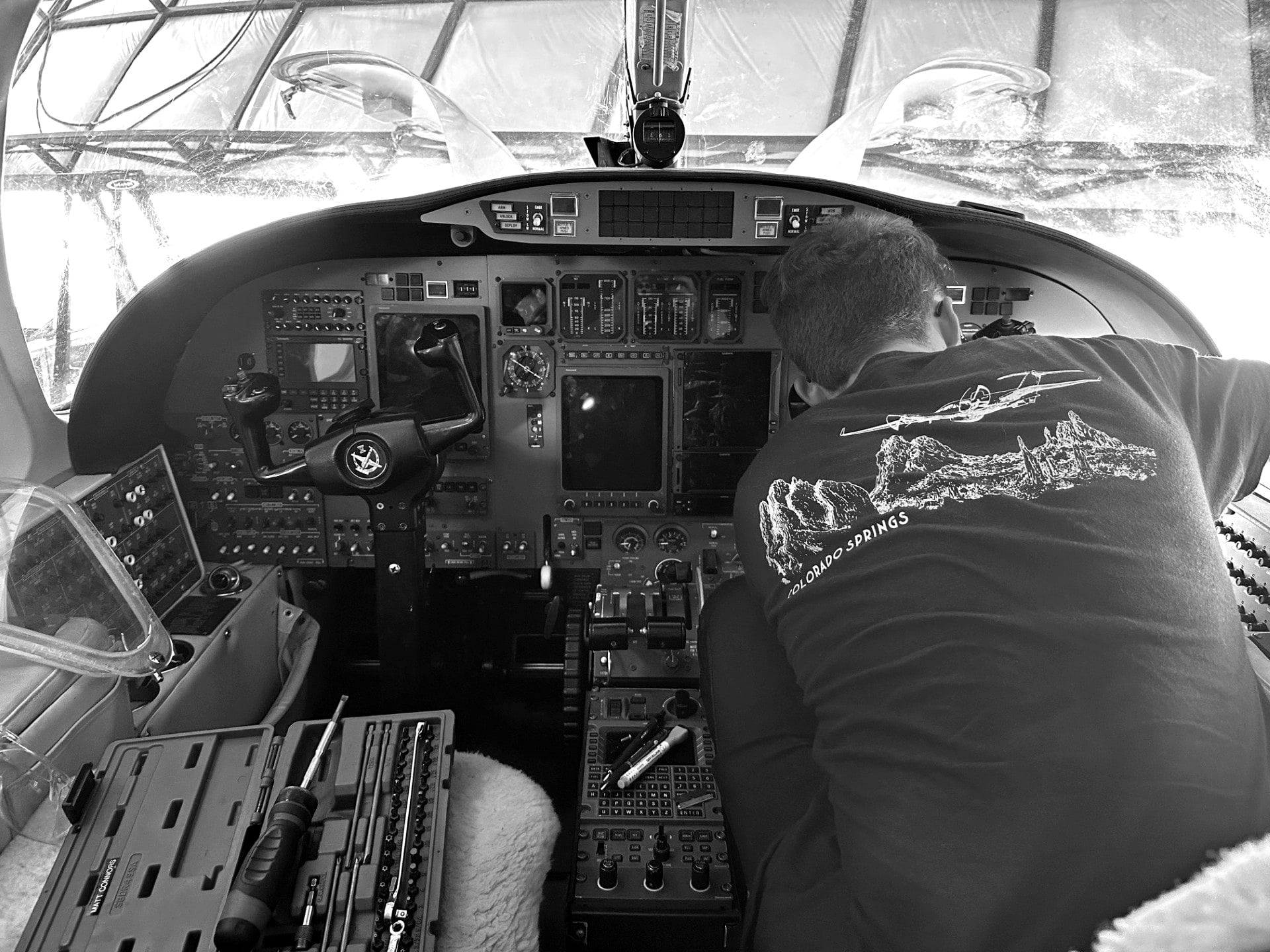 Technician leaning over the instrument panel of a Citation jet in the cockpit